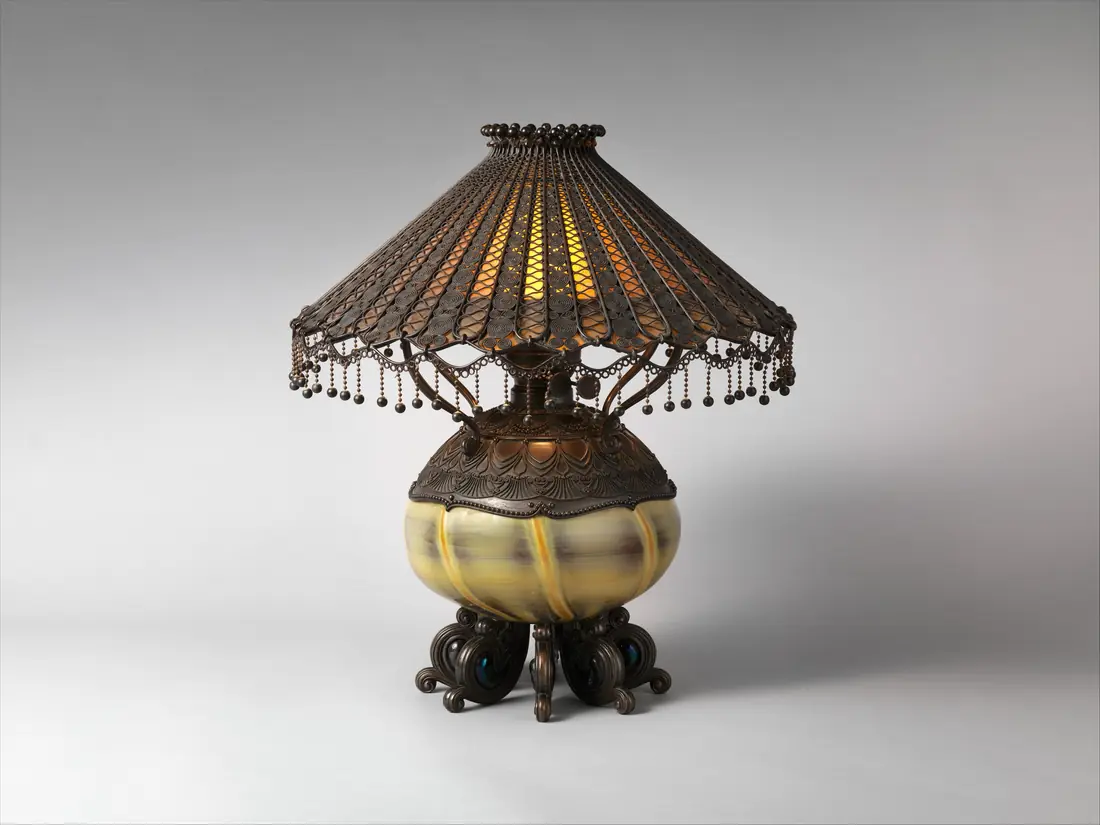 Photographie d’une lampe de table à abat-jour de verre plombé sur pied de bronze patiné, vers 1895 : une pièce fragile, dont on veut savoir à tout moment où elle en est.