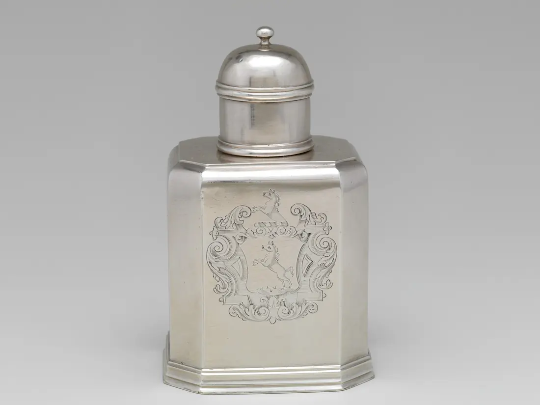 Photographie d’une boîte à thé en argent gravée d’armoiries, vers 1720, vue de face : une pièce vendue, dont la facture reprend le titre, le prix et l’acheteur.